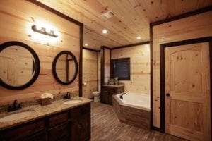 Cabin bathroom with dual vanity sinks, separate tub and shower, fireplace, television