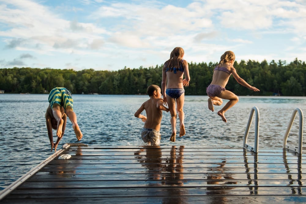 group of kids jumping into a lake