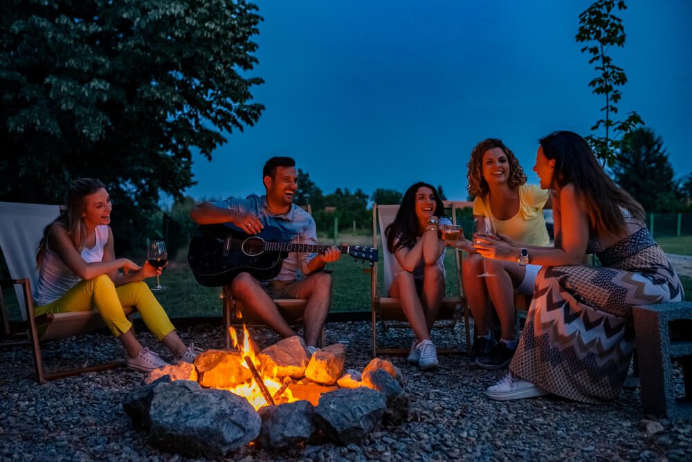 Friends gathered around a fire in Broken Bow, one of the best things to do in summer