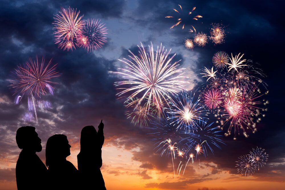 A family of three watching fireworks during a 4th of July Getaway to Broken Bow