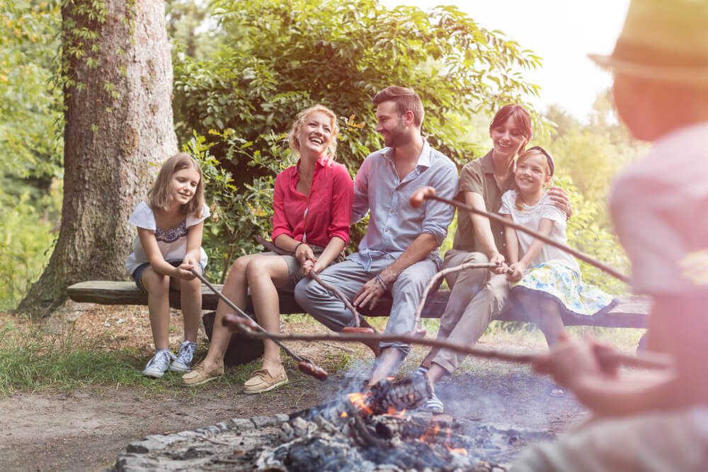 A family with young kids sitting around a fire and roasting marshmallows during a digital detox retreat