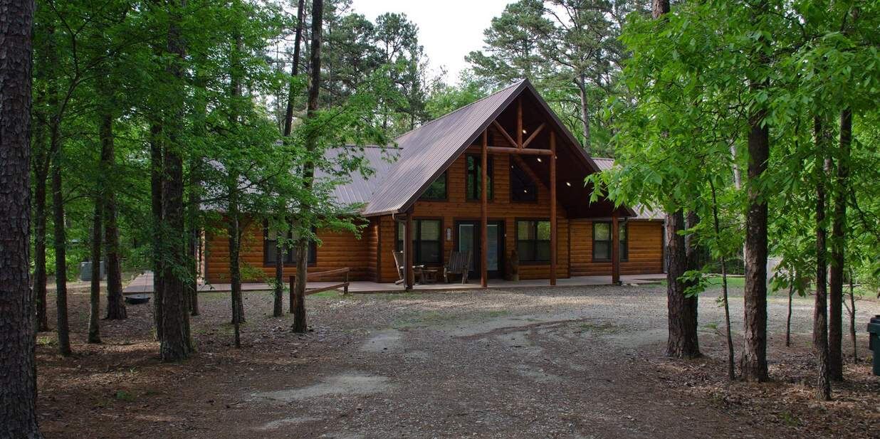 A cozy log cabin surrounded by tall trees in Broken Bow, OK