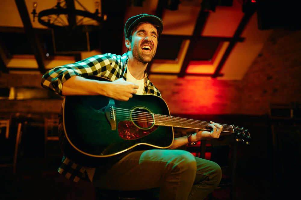 A man singing and playing guitar at a live music bar in Broken Bow, OK